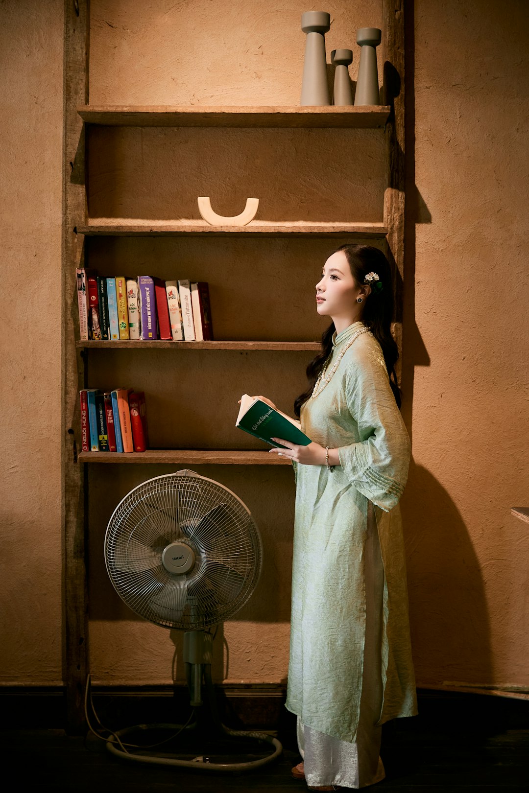 Woman in traditional dress reading a book by shelf